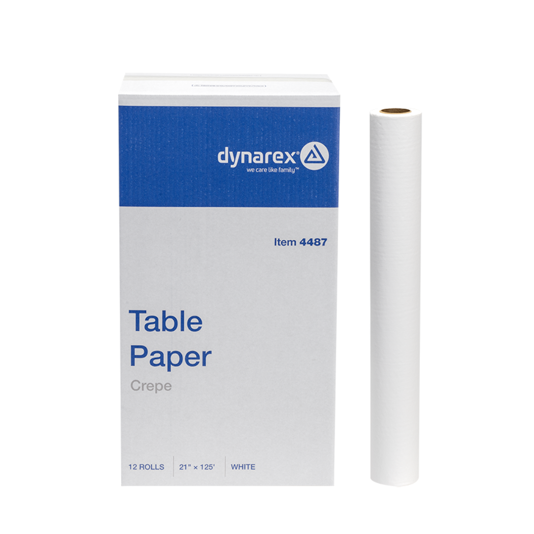 A box of Dynarex Exam Table Paper with a blue and white design stands beside a single roll. The box contains 12 white rolls, each measuring 21 x 125 inches, providing a protective barrier.